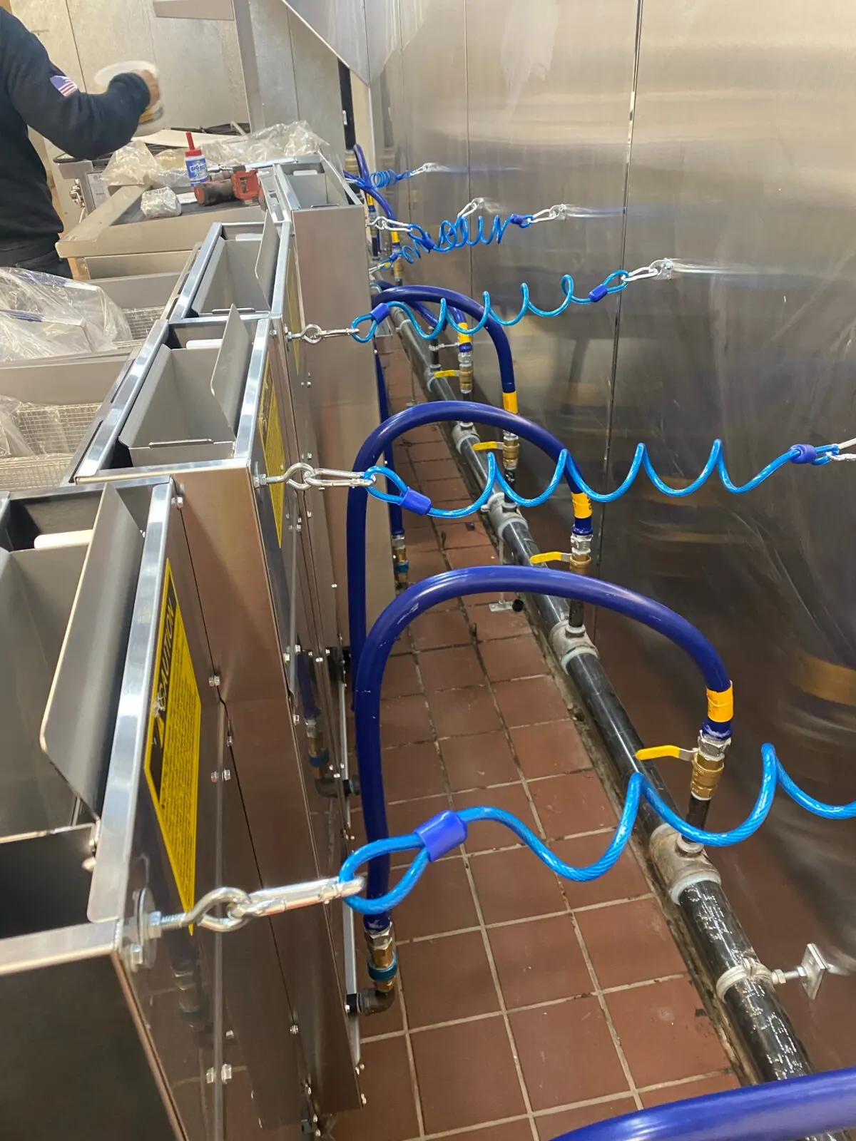 Flexible gas connectors and restraint cables behind commercial cooking equipment