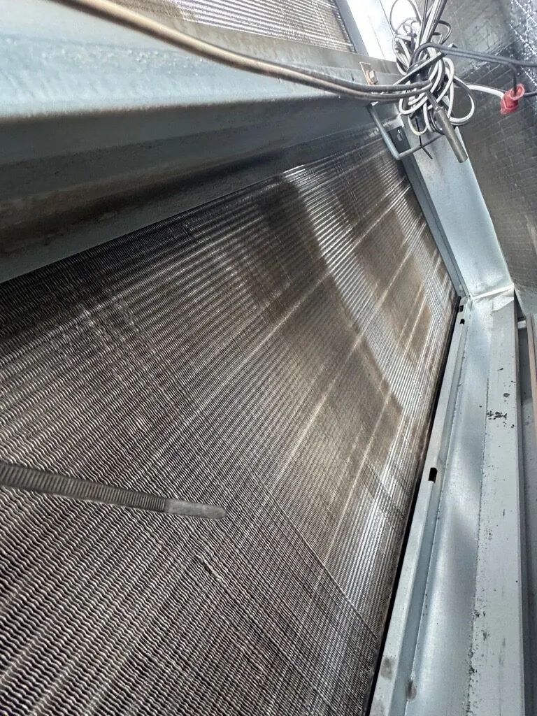 Cleaning wand being used on a rooftop coil